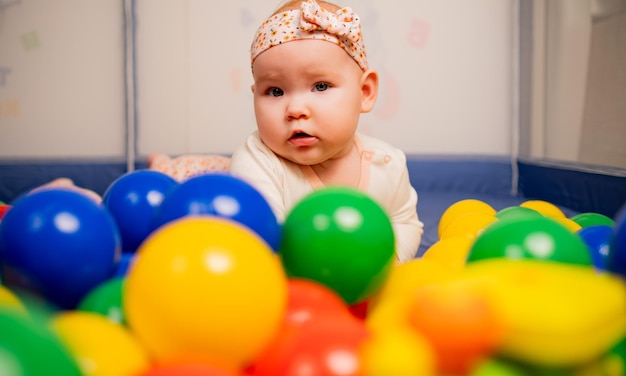 Une mignonne petite fille jouant avec des boules colorées à la maternelle.