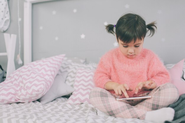 Mignonne petite fille jouant avec un téléphone intelligent, le téléphone intelligent a un impact négatif sur le développement et la santé mentale de votre enfant