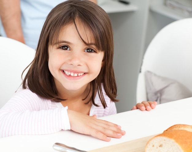 Mignonne petite fille mangeant du pain pendant le petit déjeuner