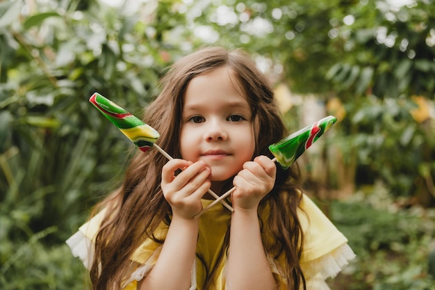 Mignonne petite fille mangeant une sucette en forme de pastèque Enfant avec des sucettes dans le jardin botanique