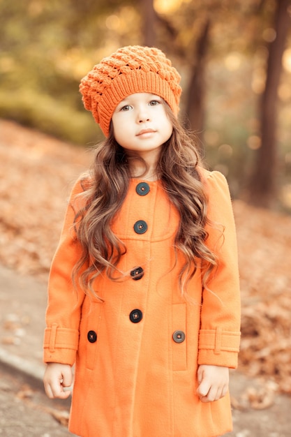 Mignonne petite fille marchant à l'extérieur portant un élégant manteau d'automne dans le parc à l'extérieur