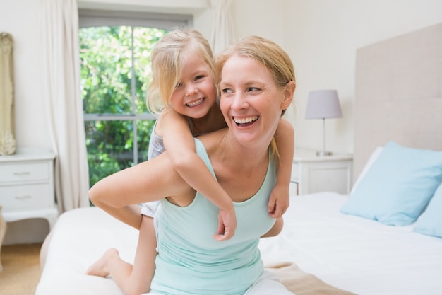 Mignonne petite fille et mère sur le lit