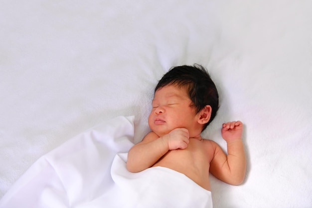 Une mignonne petite fille qui dort sur le lit.