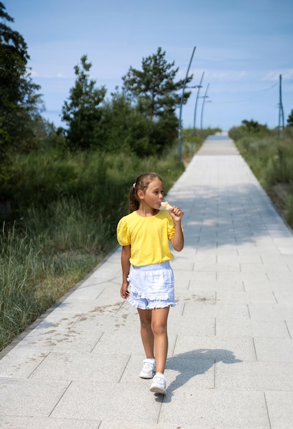 Une mignonne petite fille qui rit mange de la crème glacée par une journée chaude.