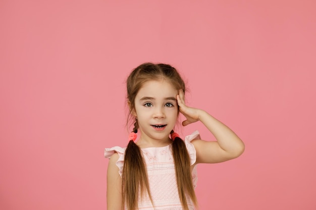 Mignonne petite fille en robe pense à quelque chose