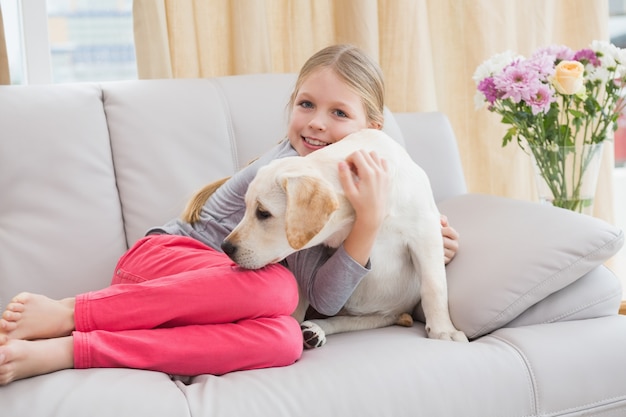 Mignonne petite fille avec son chiot sur le canapé