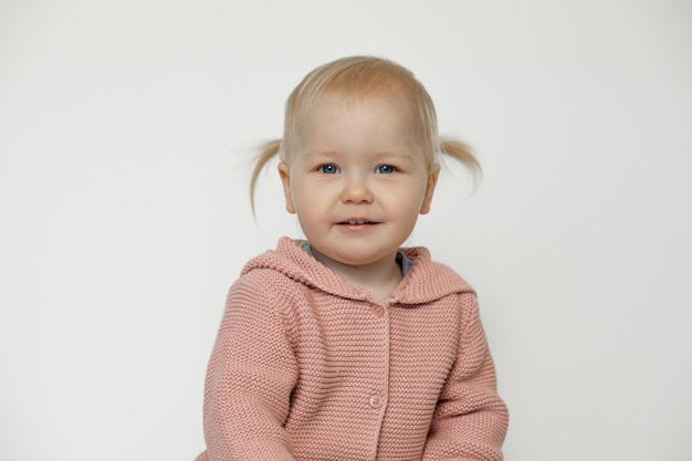 Mignonne petite fille souriante isolée sur blanc Portrait d'un enfant en bas âge heureux en studio Enfant aux cheveux blonds avec une expression faciale joyeuse en pull rose