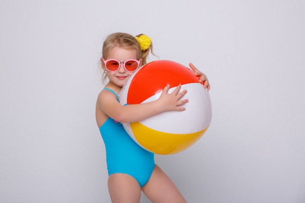 Mignonne petite fille souriante en maillot de bain avec anneau en caoutchouc isolé on white