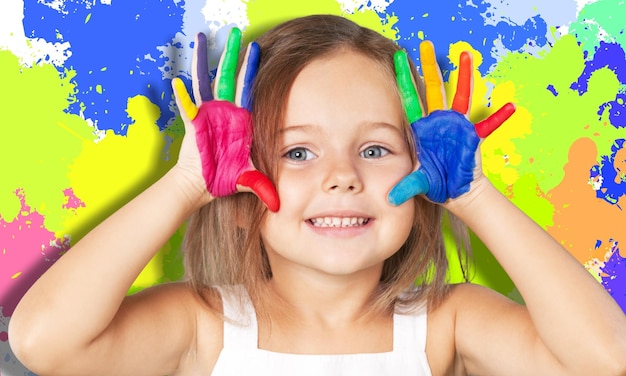 Mignonne petite fille souriante avec les mains dans la peinture isolée