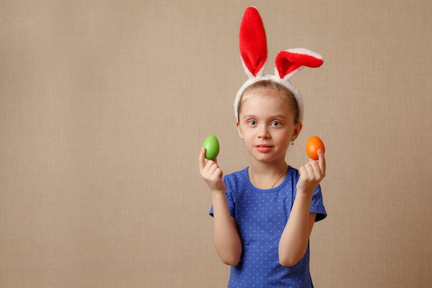 Mignonne petite fille souriante avec des oeufs de Pâques colorés. Joyeuses Pâques