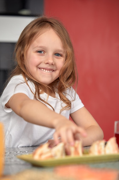 Mignonne petite fille souriante avec des sushis sur fond blanc Enfant fille mangeant des sushis et roule le concept commercial