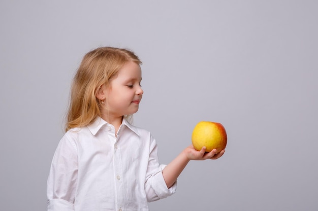 Mignonne petite fille tenant une pomme sur un fond blanc