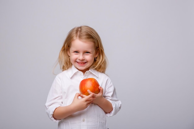 Mignonne petite fille tenant une pomme sur un fond blanc