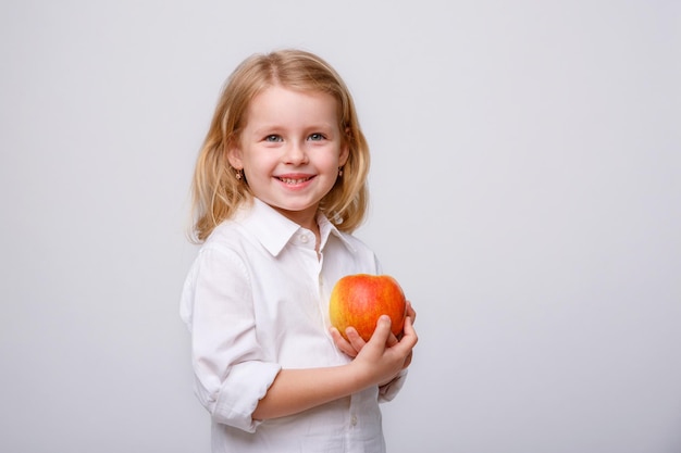 Mignonne petite fille tenant une pomme sur un fond blanc