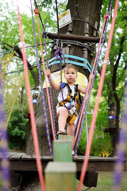 Mignonne petite fille en train d&#39;escalade sur un parc de corde