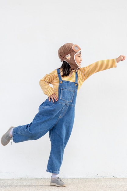 Une mignonne petite fille vêtue d'une casquette et de lunettes de pilote. L'enfant rêve de devenir pilote.