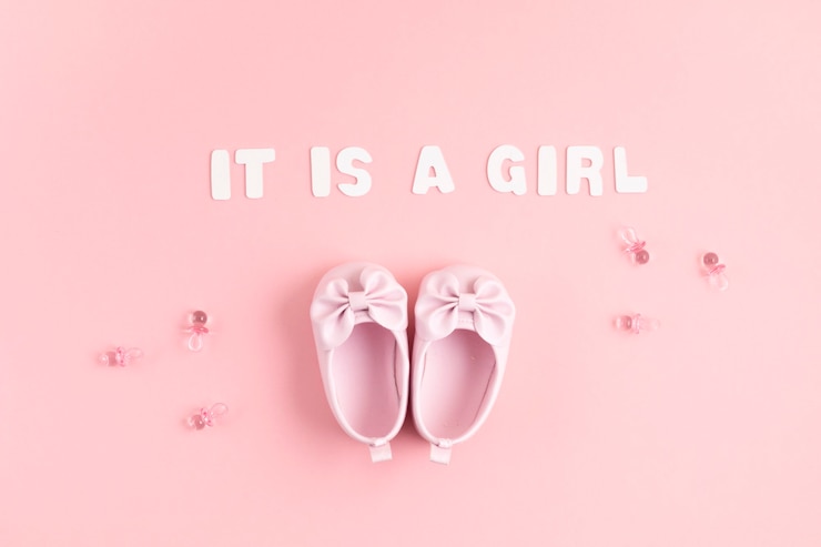Photo mignonnes chaussures de bébé nouveau-né avec décoration festive sur mur rose.