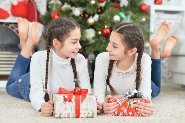 Mignonnes petites filles avec un cadeau près d'un sapin de Noël décoré