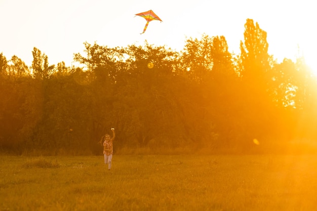 Mignonnes petites filles avec cerf-volant dans le champ au coucher du soleil