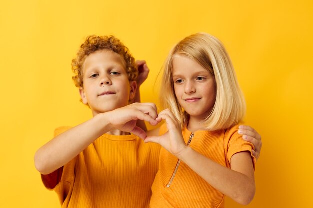 Mignons enfants d'âge préscolaire en t-shirts jaunes debout côte à côte émotions de l'enfance fond jaune