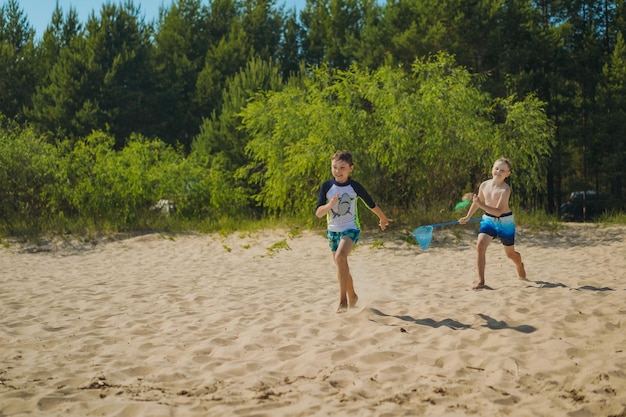 Mignons garçons caucasiens qui courent le long de la plage de sable dans l'eau avec des rires Vacances au bord de la mer Enfance heureuse