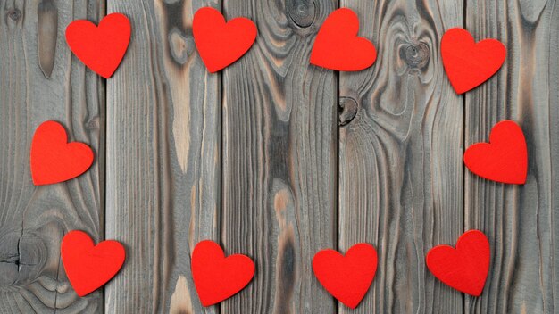Mignons petits coeurs rouges portant avec trou dans le cercle sur fond de bois foncé Saint Valentin femmes fête des mères