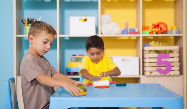 Mignons petits garçons jouant avec de la pâte à modeler dans la salle de classe