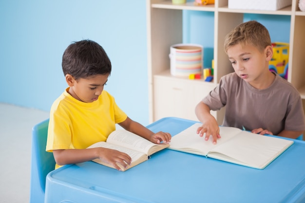 Mignons petits garçons lisant au bureau dans la salle de classe à l&#39;école maternelle