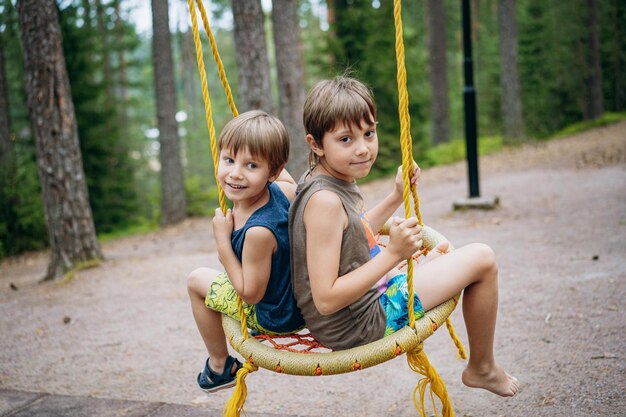 Mignons petits garçons s'amusant sur une balançoire à l'aire de jeux