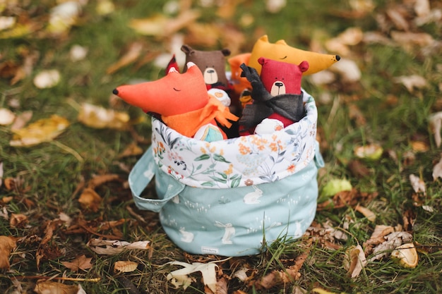 De mignons petits jouets sont assis dans un panier dans le jardin d'automne