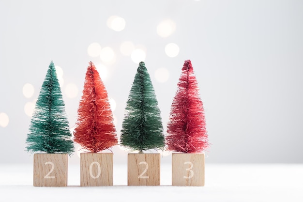 Mignons sapins miniatures de Noël sur un tableau blanc avec des lumières bokeh