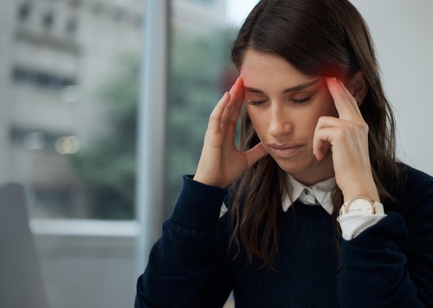 Cette migraine est chaude Photo d'une jeune femme d'affaires qui a mal à la tête au travail