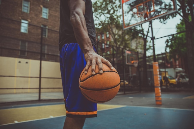 Le milieu d'un jeune homme tenant un basket-ball à la cour