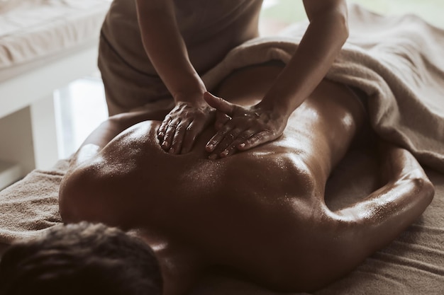 Photo le milieu d'une masseuse donnant un massage à une femme au spa