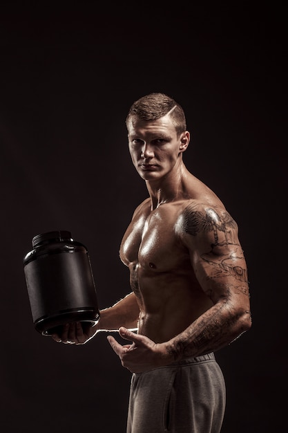 Milieux De Sport. Bodybuilder Fort Tenant Un Pot En Plastique Avec Une Protéine Sèche Isolée. Aliments Pour Sportifs