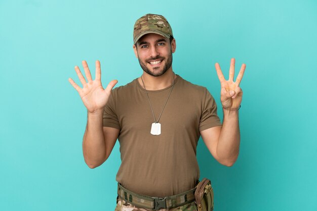 Militaire avec dog tag sur isolé sur fond bleu comptant huit avec les doigts