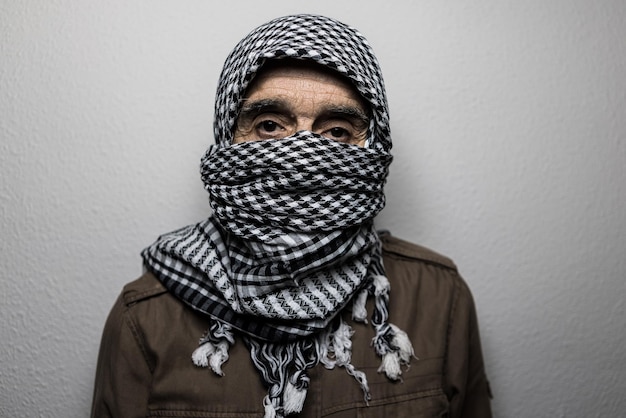Un militaire portant un foulard palestinien ou un shemagh couvrant son visage sur un fond blanc