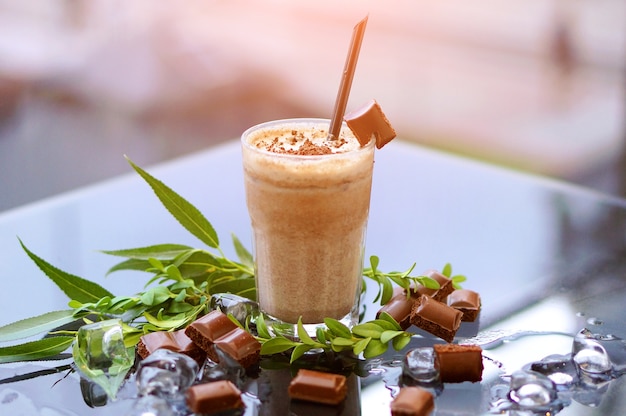 Milk-shake au chocolat à la menthe fraîche et de la glace sur la table en verre avec arrière-plan flou