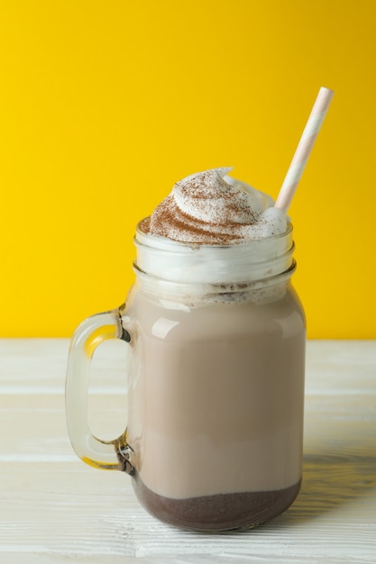 Milk-shake au chocolat sur table en bois contre mur jaune