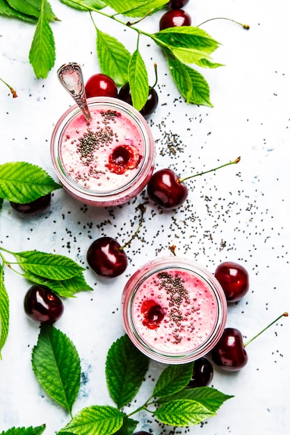 Milk-shake aux cerises roses avec baies et graines de chia fond de pierre blanche vue de dessus