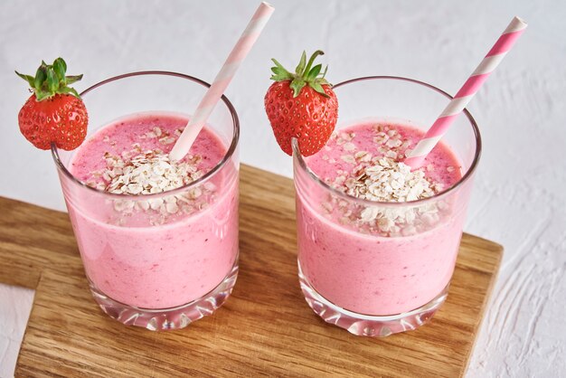 Milk-shake aux fraises en verre avec de la paille et des baies fraîches