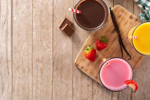 Milk-shakes au chocolat, fraises et vanille sur table en bois rustique