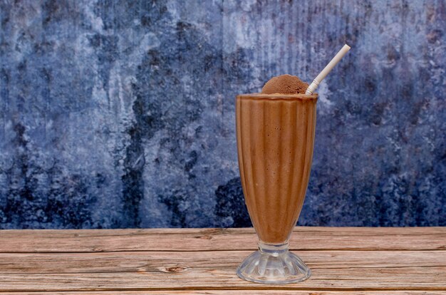 Milkshake au chocolat dans une tasse en verre sur une table en bois