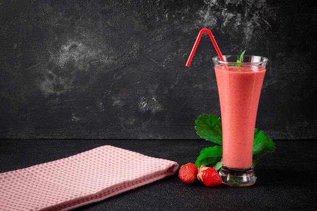 Milkshake aux fraises à la menthe poivrée dans un verre sur fond de pierre sombre. Une alimentation saine pour le petit-déjeuner et les collations.