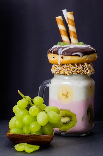 Milkshake (cocktail) avec kiwi et banane en verre avec une grappe de raisin