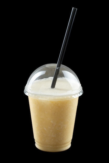 Milkshake avec crème glacée, jus et sirop de fruits en verre plastique isolé sur fond noir