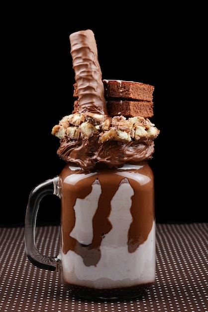 Milkshake extrême au chocolat avec gâteau au brownie, pâte de chocolat et bonbons. Tendance folle de la nourriture freakshake. Espace de copie