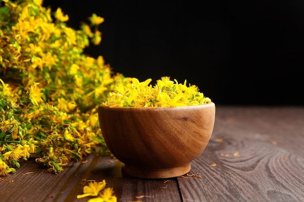 Le millepertuis (Hypericum perforatum) fleurs jaunes dans un bol en bois