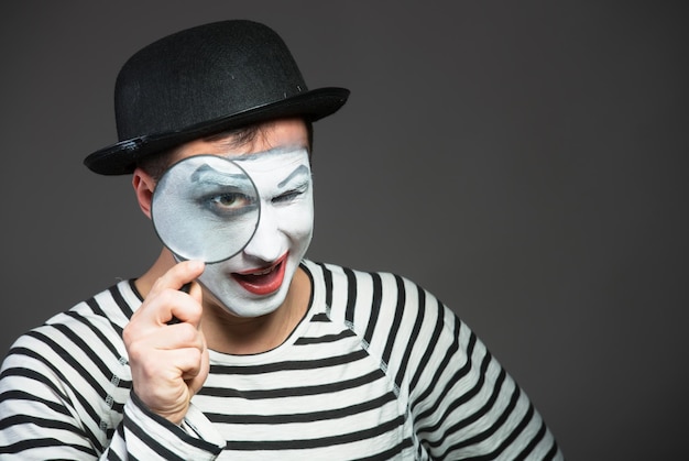 Mime mâle regardant à travers la loupe