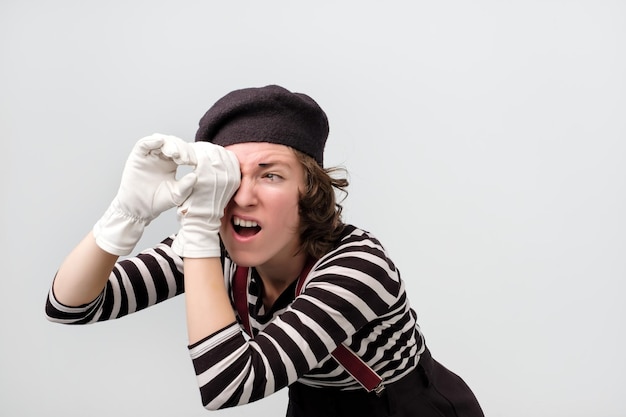 Mime regardant à travers ses doigts comme des jumelles cherchant quelque chose